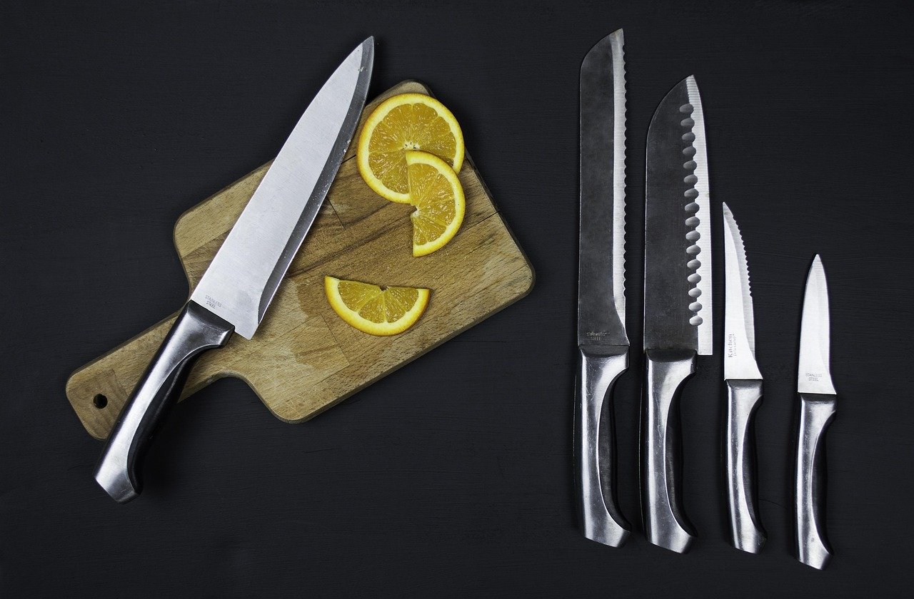 Butcher hands using a sharp boning knife to trim fresh meat cuts on a white board